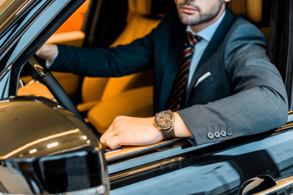 partial view of businessman with luxury watch sitting in automobile
